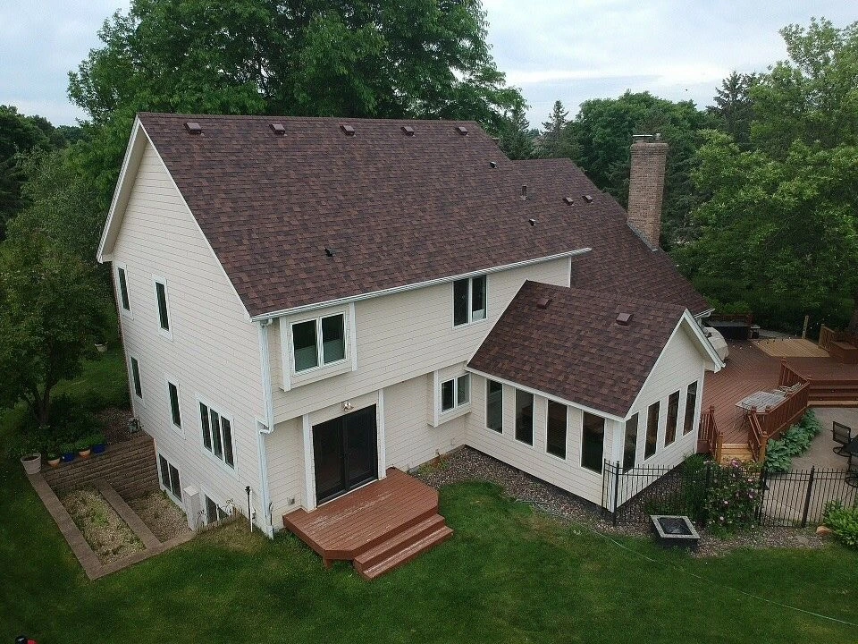 Pale Yellow Residential Home in Rochester, Minnesota with a new roof asphalt shingle roof replacement courtesy of Built Strong Exteriors. 